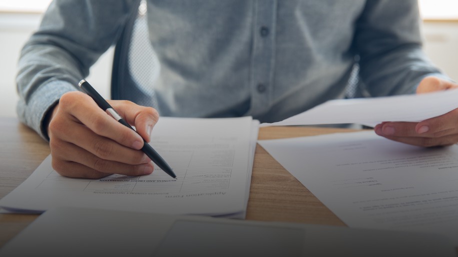 Person reviewing insurance documents at desk with laptop