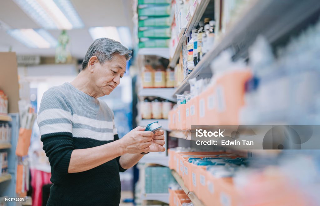 Older man looking at a product in the aisle of a pharmacy