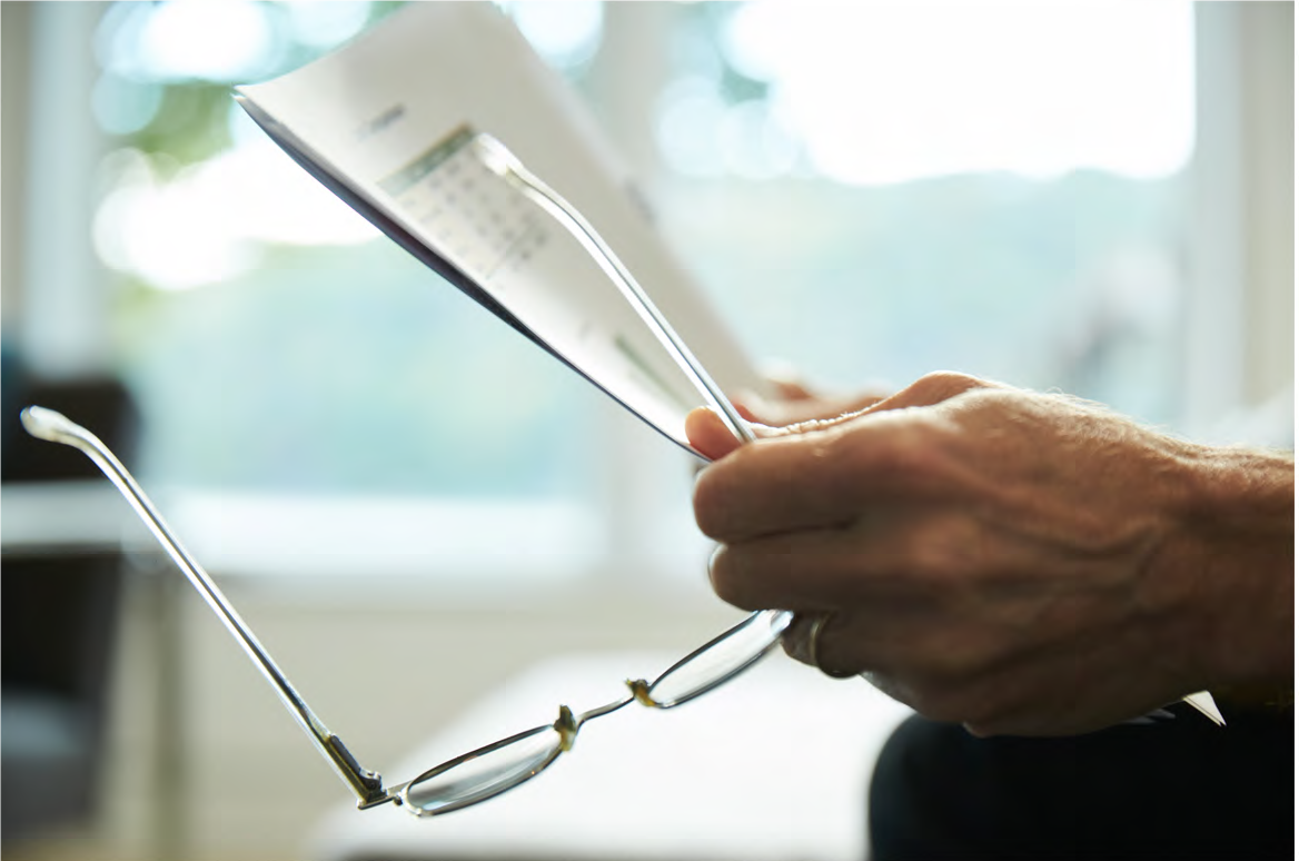 Man holding glasses and paper in hand